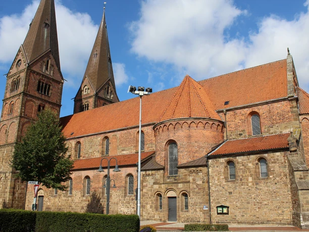 Stiftskirche Bücken Historic Bücken collegiate church with two striking towers under a blue sky, surrounded by nature.