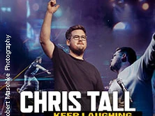 Chris Tall auf der Bühne, hebt die Hand in einer dynamischen Pose, farbenfrohe Lichter im Hintergrund.