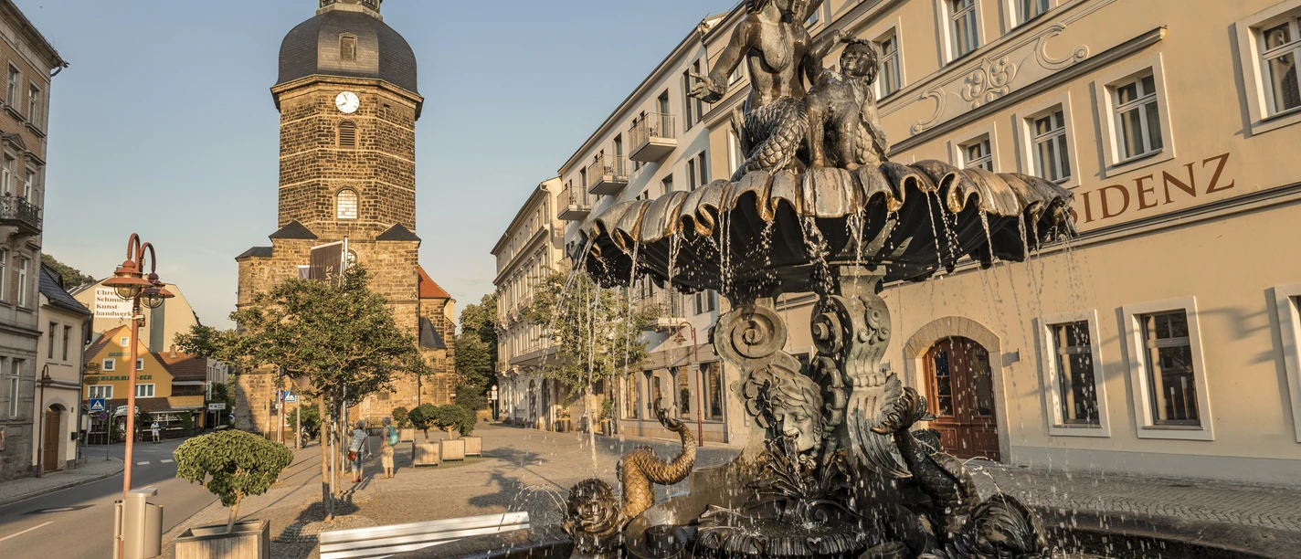 Het oude marktplein van Bad Schandau, gedomineerd door een sierlijke fontein en een opvallende gevel met kerktoren.