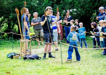 Aktionen auf dem Museumsfest Eine Gruppe von Menschen, darunter Kinder, versammelt sich um eine Bogenschießstation im Freien.