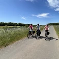 Drei Fahrradfahrer fahren auf einem ländlichen Weg unter blauem Himmel in der Mittelweser-Region.