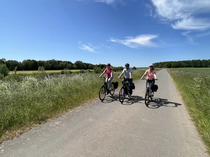 Fahrradfahrer in der Mittelweser-Region Drei Fahrradfahrer fahren auf einem ländlichen Weg unter blauem Himmel in der Mittelweser-Region.Three cyclists ride along a rural path under a blue sky in the Mittelweser region.Tre cyklister kører ad en landlig sti under en blå himmel i Mittelweser-regionen.Drie fietsers rijden over een landelijk pad onder een blauwe hemel in de regio Mittelweser.