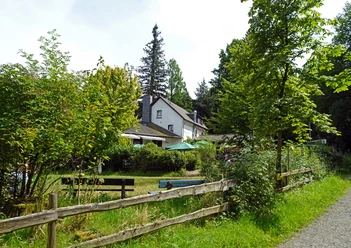 Haus Hardt Gemütliches Landhaus mit Terrasse, umgeben von üppigem Grün und einem Holzlattenzaun im Vordergrund.
