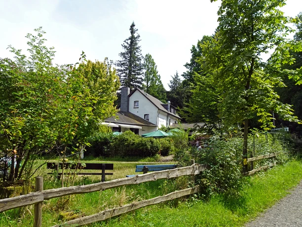 Haus Hardt Gemütliches Landhaus mit Terrasse, umgeben von üppigem Grün und einem Holzlattenzaun im Vordergrund.