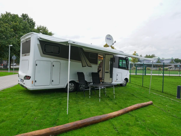 Wohnmobilstellplatz an der Welle Gütersloh Wohnmobil auf grünem Stellplatz neben Freizeitbad, mit Markise, Tisch und Stühlen