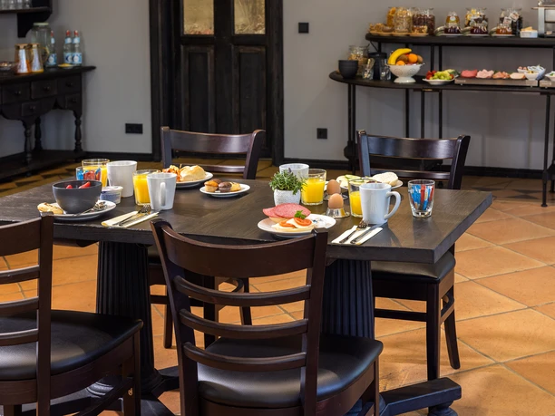 Hotel Stadt Gütersloh Gedeckter Frühstückstisch mit Brötchen, Obst, Eiern und Getränken im Frühstücksraum