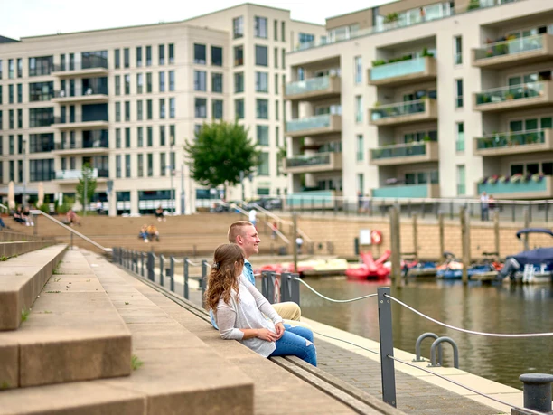 Stadthafen, Mülheim an der Ruhr Zwei junge Erwachsene sitzen im Sommer auf den Treppen am Mülheimer Stadthafen