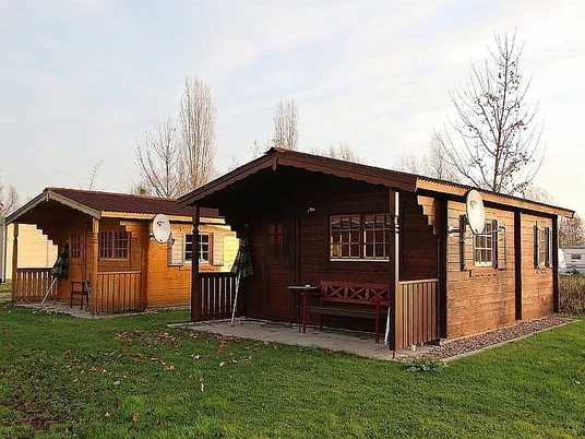 Campingplatz Axelsee - Hütte Im vorderen Bereich Rasenfläche, zwei Hütten aus Holz nebeneinander