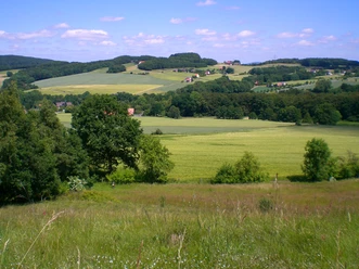 Bonstapel-A2_Blick vom Selberg.JPG Landschaft mit grünen Feldern, sanften Hügeln und verstreuten Höfen unter blauem Himmel mit Wolken.
