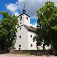 Kath. Pfarrkirche Hl. Familie und Hl. Stephanus in Wehrden Weißes Kirchengebäude mit runden Fenstern und Turm, links- und rechtsseitig von Bäumen umgeben