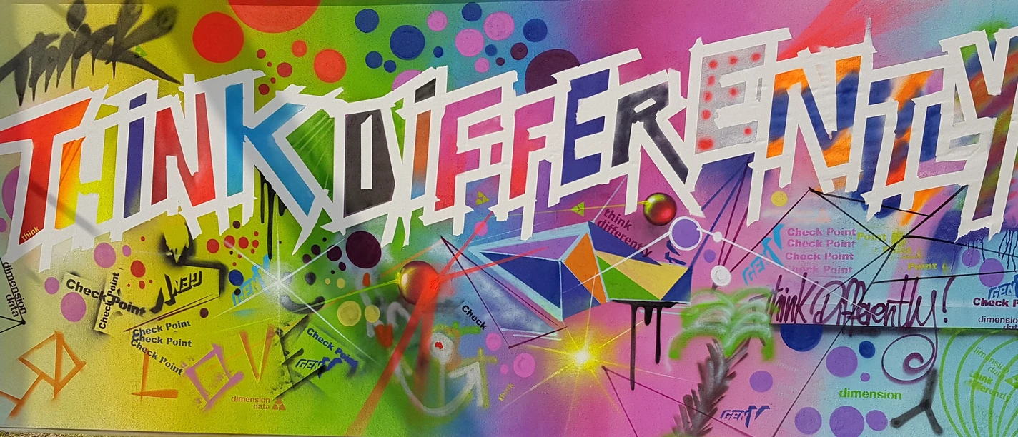 COLORI Events Graffiti wall with "Think Differently", in front of it colorful spray cans.