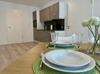 Wohn- und Essbereich.JPEG Moderner Wohn- und Essbereich mit hölzerner Küchenzeile, gedecktem Tisch und hellen Bodendielen.