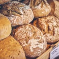 Bäckerei Brandmeier Frisch gebackene, rustikale Brote in einem Regal in einer Bäckerei.