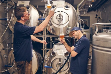 Bierbrauerei im Hotel Garmischer Hof Zwei Brauer im Hotel Garmischer Hof prüfen Bierproben vor Edelstahlbrautanks.