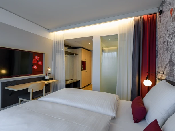 Ein modernes Hotelzimmer mit Doppelbett, dezenter Beleuchtung und einer Wand mit Stadtkarte als Design.