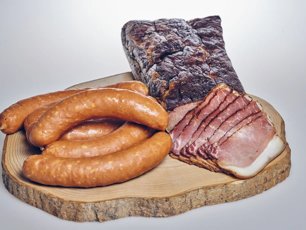 Metzgerei Haller Geräucherte Würste und geschnittener Schinken auf einem Holzbrett.