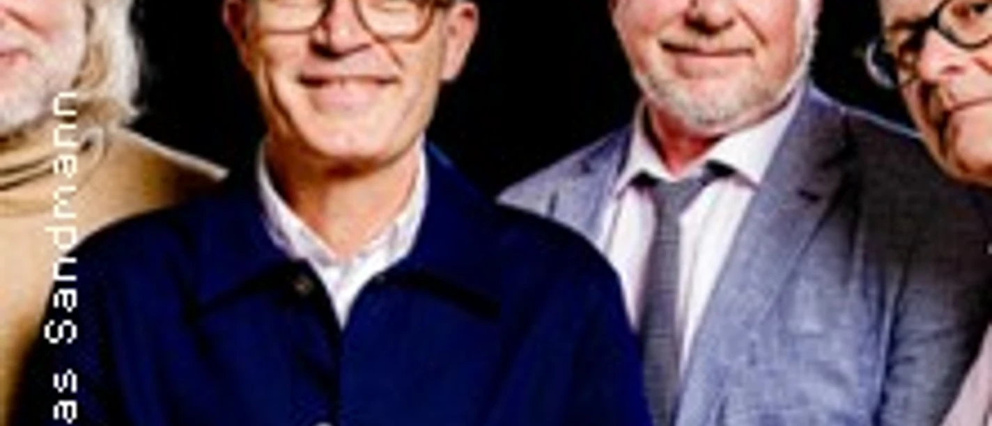 Die Band Erdmöbel in einer Reihe, mit lächelnden Gesichtern in formeller Kleidung.