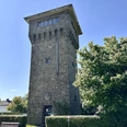 Hindenburgturm Ein historischer Wasserturm aus Stein, umgeben von Bäumen, unter einem klaren blauen Himmel.