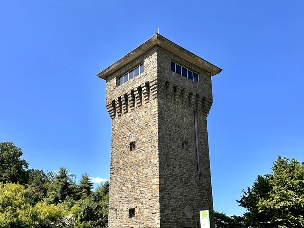 Hindenburgturm Ein steinerner Aussichtsturm mit rechteckigem Grundriss steht unter klarem Himmel, umgeben von Bäumen.