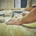 Bäckerei Sand Bäckerhände kneten Teig auf einer bemehlten Arbeitsfläche.