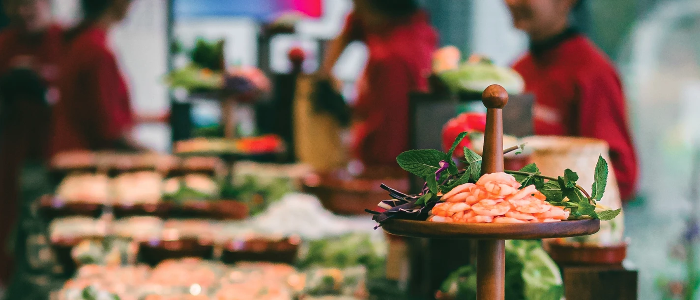 District Banh Mi GmbH Buffet mit vietnamesischen Speisen, im Hintergrund stehen Servicekräfte.