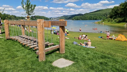Barfusspfad Hennesee Wackelbrücke Auf dem Bild ist ein lebendiger Barfußpfad am Hennesee zu sehen. Menschen entspannen auf der Wiese.