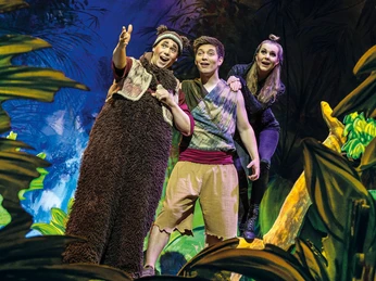 Dschungelbuch - das Musical 2 (c) Theater Liberi.jpg Drei Darstellende in Kostümen auf einer bunten Bühnenlandschaft. Einer zeigt mit erhobenem Arm auf etwas in der Ferne und die beiden anderen staunen.