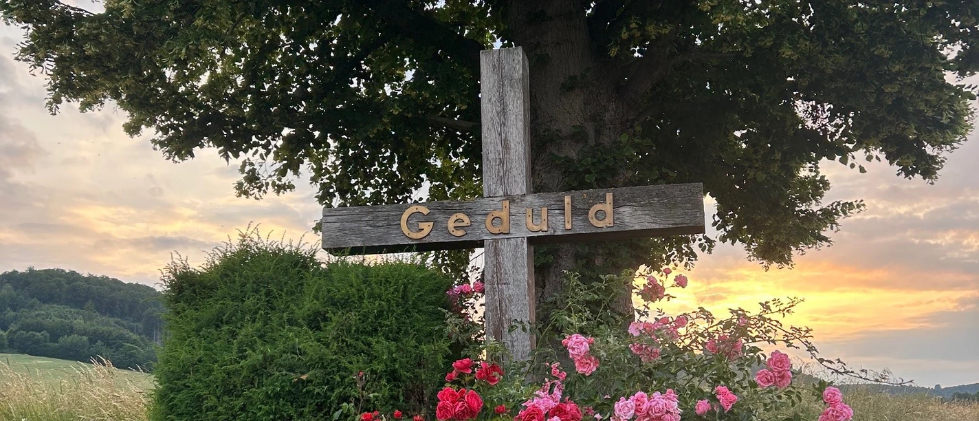 kreuz_godelheim_mariealthaus.jpg Schönes Holzkreuz unter einem Baum mit Bepflanzung