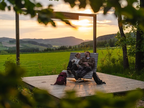 Wanderbank in Küstelberg Ein Wanderpaar sitzt auf einer Bank im Sonnenuntergang in Küstelberg