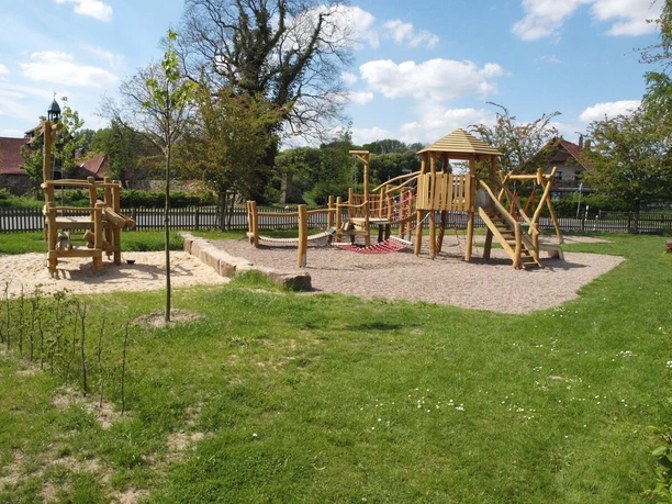 Spielplatz Begegnungsstätte Stockhausen in Lübbecke Spielplatz mit Holzklettergerüst und Rutsche in grüner Umgebung, geeignet für Kinderaktivitäten.