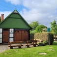 Ortsteil Stockausen Lübbecke Fachwerkhaus mit grünem Giebel, Spielplatz im Hintergrund, Bänke und Hecken im Vordergrund.