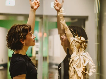 Freiheit 4_Isabel Noack.jpg Frau betrachtet fasziniert ein Modell der Freiheitsstatue hinter Glas in einem Museum.Woman looking fascinated at a model of the Statue of Liberty behind glass in a museum.Žena fascinovaně hledí na model Sochy svobody za sklem v muzeu.Kobieta patrzy zafascynowana na model Statuy Wolności za szybą w muzeum.Vrouw kijkt gefascineerd naar een model van het Vrijheidsbeeld achter glas in een museum.Donna che guarda affascinata un modello della Statua della Libertà dietro un vetro in un museo.