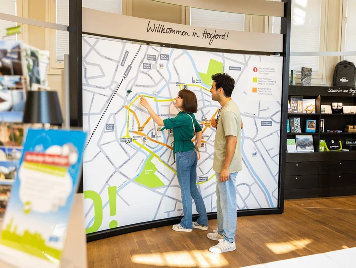 herford-tourist-info-teutoburger-wald-tourismus-h-tornow-001-jpg.jpg Zwei Personen betrachten eine große Karte der Innenstadt von Herford in einer Touristeninformation.