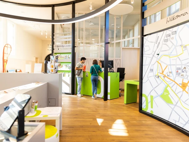 Heller und moderner Innenbereich eines Touristenzentrums mit Informationsschalter und Kartenanzeige.