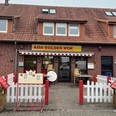 Golden Wok.jpg Das Bild zeigt das Restaurant Asia Golden Wok, ein Backsteingebäude mit roten Dachziegeln. Vor dem Eingang gibt es weiße und rote Absperrungen, Blumenhäuschen und eine Speisekarte.