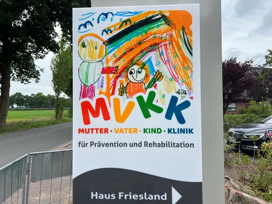 MVKK.Logo.jpg Das Schild zeigt ein buntes Logo der "Mutter-Vater-Kind-Klinik" mit Kindern in fröhlichen Farben.