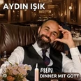 Aydın Işık sitzt lächelnd in einem eleganten Restaurant, den Kopf auf die Hand gestützt.