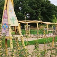 Ein lebhafter Spielplatz mit hölzernen Klettergeräten, Seilbrücke und fröhlichen Farben, umgeben von grüner Vegetation. Ideal für Kinder, um sich auszutoben und die Natur zu genießen.