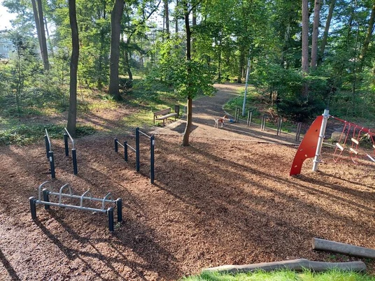 Spielplatz Am Rodelberg Der Spielplatz Am Rodelberg liegt idyllisch im Wald und bietet vielfältige Klettergerüste und Fitnessgeräte auf einem weichen Rindenmulchuntergrund.