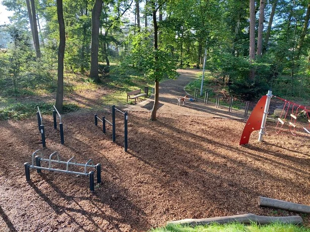 Spielplatz Am Rodelberg Der Spielplatz Am Rodelberg liegt idyllisch im Wald und bietet vielfältige Klettergerüste und Fitnessgeräte auf einem weichen Rindenmulchuntergrund.