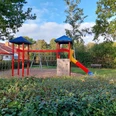 Spielplatz Dresdner Straße Ein farbenfroher Spielplatz mit Kletterturm, Rutsche und Kletterwand, umgeben von Bäumen und Sträuchern.