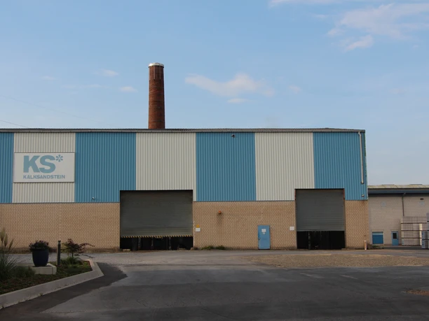 POI-2-Kalksansteinwerk.JPG Ehemaliges Kalksandsteinwerk mit charakteristischem, hohem Ziegelschornstein, umgeben von Asphalt.