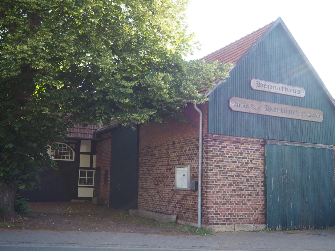 Heimathaus Hartum Das Heimathaus Hartum, ein historisches Fachwerkgebäude, flankiert von altem Baumbestand.