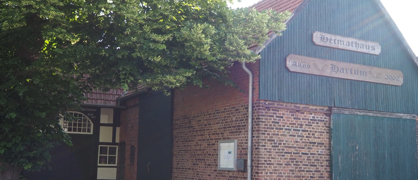 Heimathaus Hartum Das Heimathaus Hartum, ein historisches Fachwerkgebäude, flankiert von altem Baumbestand.