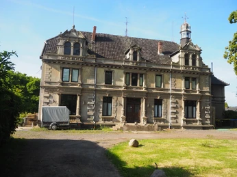 Herrenhaus Südhemmern Ein historisches Herrenhaus mit verzierten Giebeln und großen Fenstern auf einem gepflegten Grundstück.