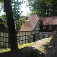 Husenmühle im Nachtigallental Die "Husenmühle im Nachtigallental" ist eine charmante, historische Fachwerkmühle, die idyllisch inmitten von Bäumen liegt. Das Gebäude aus weißem Fachwerk mit dunkelbraunen Holzbalken und einem roten Ziegeldach fügt sich harmonisch in die grüne Umgebung ein. Die Mühle strahlt eine beruhigende ländliche Atmosphäre aus.