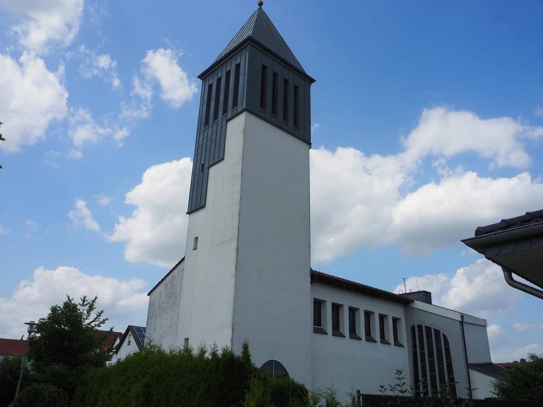 St Raphaels Kirche Weiße Kirche mit hohem rechteckigen Glockenturm, blauer Himmel im Hintergrund, umgeben von grünen Bäumen.