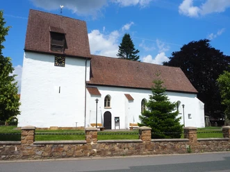 Die St.-Ulricus-Kirche erstrahlt vor strahlend blauem Himmel. Sie zeigt eine schlichte weiße Fassade mit einem markanten quadratischen Turm und einem Ziegeldach.