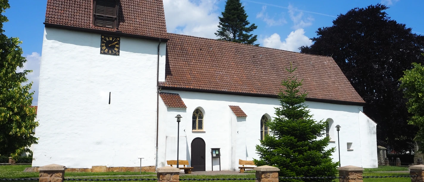 Die St.-Ulricus-Kirche erstrahlt vor strahlend blauem Himmel. Sie zeigt eine schlichte weiße Fassade mit einem markanten quadratischen Turm und einem Ziegeldach.
