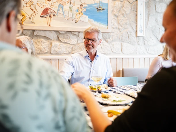 Stadtführungen © Matheus Fernandes (98).jpg Eine fröhliche Gruppe beim Essen in einem gemütlichen, lichtdurchfluteten Restaurant mit Kunstwerken.